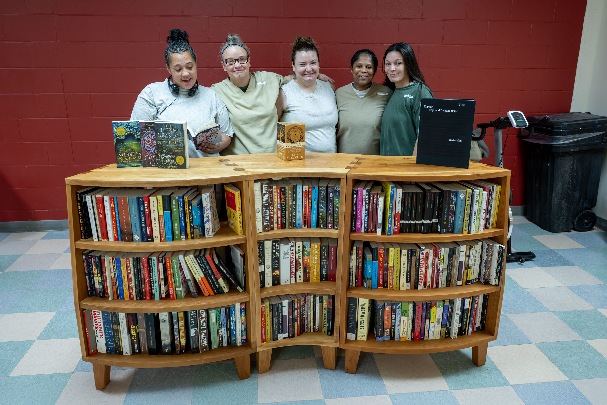 Five Women's Eastern Reception, Diagnostic and Correctional Center (WERDCC) residents pose with a paperback-filled bookcase installed by the nonprofit organization Freedom Reads.