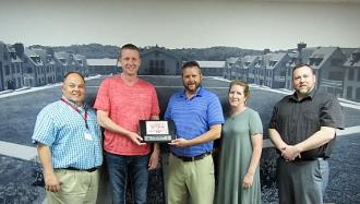 Five staff members holding a plaque.