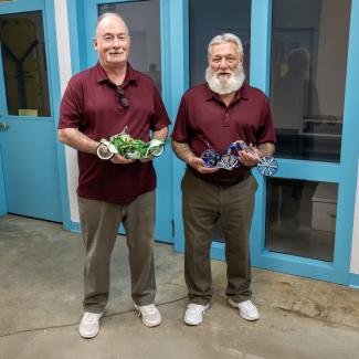 Portrait of Mark Eighinger and Richard McCool holding motorcycle models
