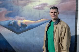 Booth stands in front of his mural depicting the B-2 Stealth Bomber